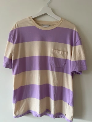 Randig lila och beige t-shirt - Säljer en oversized t-shirt med lila och beigea ränder. Bra skick, endast använd ett fåtal gånger 