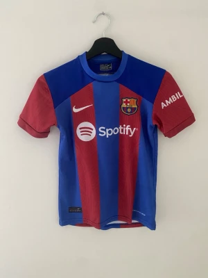 Barcelona matchtröja 23/24 Pedri #8 - Säljer en FC Barcelona matchtröja 2023/24 från Nike med Pedri #8 på ryggen. Tröjan har klubbmärke och sponsorloggor på bröstet samt tryck på ärmarna. Tillverkad i lätt och ventilerande material, perfekt för fotboll. Den har storlek 14 i fotbollströjor så har testat och anser den som storlek 140.