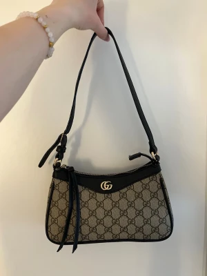 Gucci väska  - Säljaren supersnygg oäkta Gucci väska med ett Reglerbart Axel remband. Väskan är bara använd ett par få gånger och den enda deffekten är att det är guldiga Gucci-märket tappat lite lite färg, vilket knappast syns. Köpte den för 2500 kr på vinted men kommer nu inte till användning. Ställ jättegärna frågor!❤️