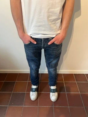 Dondup jeans  - Säljer ett par riktigt feta mörkblå jeans från Dondup i slim med snygga slitningar. Passar perfekt nu inför sommaren. Hör av er vid intresse eller frågor. Dondups storlekar är lite skumma men W33. Modellen är 180 cm och väger 65 kg