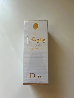 J'adore Eau de Parfum från Dior - Helt ny J'adore Eau de Parfum från Dior i en elegant vit och guldig förpackning. Parfymen är känd för sin lyxiga och blommiga doft, och flaskan rymmer 50 ml. Perfekt för dig som vill ha en ikonisk och feminin parfym från ett exklusivt märke. Hör av er vid minsta lilla fråga. Priset kan diskuteras vid snabb affär. 