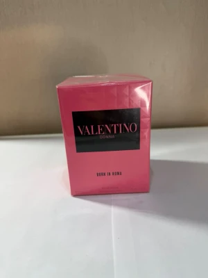 Valentino Donna Born In Roma parfym - Valentino Donna Born In Roma är en lyxig parfym i en snygg rosa kartong med svarta detaljer. Förpackningen har en modern och elegant design med geometriskt mönster. Perfekt för dig som gillar exklusiva dofter och vill ha något som sticker ut i badrumshyllan.
