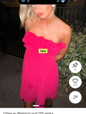 Axelbandslös rosa kortklänning - Snygg axelbandslös rosa klänning med volangdetaljer upptill. Klänningen är kort och har en luftig, lätt form som passar perfekt för varma dagar. Tillverkad i ett tunt och flowy material som ger en skön känsla.
