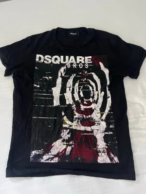 Svart DSQUARED2 grafisk t-shirt - Cool svart t-shirt från DSQUARED2 med stort grafiskt tryck i vitt, rött och gult på framsidan samt texten 'DSQUARE BROS'. Nypris: 2799kr