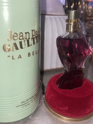 Jean Paul Gaultier La Belle parfym - Jean Paul Gaultier La Belle Eau de Parfum i en unik flaska formad som en kvinnokropp. Flaskan är djupt vinröd med gulddetaljer och kommer i en mintgrön förpackning med guldtext. En ikonisk och lyxig doft för dig som vill sticka ut.