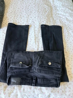 Svarta jeans från Perfect Jeans - Säljer ett par svarta jeans från Perfect Jeans i storlek 36. Jeansen har raka ben, två bakfickor med lock och silverfärgade knappar. Klassisk femficksmodell i mjukt denimtyg som passar till det mesta. 