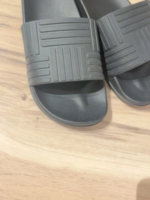 Bottega veneta tofflor svart - Svarta bottega veneta tofflor med svarta sträck på toppen av tofflorna. perfekta för sommaren!