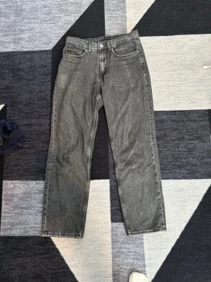 Grå raka jeans från Weekday - Säljer ett par grå raka jeans från Vailent med klassisk femficksdesign och normal midja. Jeansen har en tvättad look och raka ben, perfekta för en avslappnad stil. Materialet är denim i bomull.