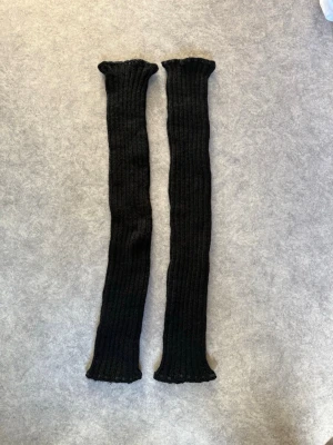 Svarta benvärmare  - Säljer ett par långa, svarta, ribbstickade benvärmare i mjukt och stretchigt material. Bra skick. 