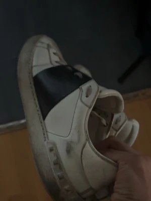 Valentino open - Snygga sneakers från Valentino i vitt läder med svarta detaljer över mitten och klassisk logga på plösen. Skorna har rund tå, vita snören och en chunky sula. Perfekta för dig som gillar exklusiva och trendiga märken.