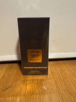 Tom Ford Tobacco Vanille 100 ml - Tom Ford Tobacco Vanille Eau de Parfum i en lyxig mörkbrun rektangulär kartong med gulddetaljer. Doften är känd för sina varma och kryddiga toner av tobak och vanilj. Flaskan rymmer 100 ml och passar dig som gillar exklusiva och unika parfymer.