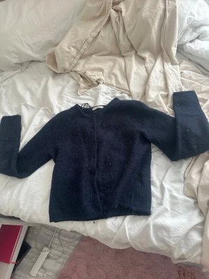 Svart kofta från Gina Tricot - Mysig marinblå kofta från Gina Tricot med knappar framtill. Koftan är stickad i ett fluffigt material och långa ärmar. Perfekt för lager-på-lager och chill dagar.