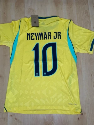 Neymar Jr #10 – Player Edition Brasilien (storlek M) - Neymar Jr #10-tryck. Player Edition Brasilien. Storlek M. Helt ny och aldrig använd. Säljs i befintligt skick. Skickas snabbt! 🚚💨  Mått för denna tröja (storlek M): (Uppmätta av leverantör – viss variation kan förekomma) • Halva bröstmåttet: 51 cm • Tröjans längd: 72,5 cm • Ärmbredd: 22,5 cm • Axelbredd: 43 cm • Ärmlängd: 39 cm • Manschettbredd: 18 cm  🔥 Player Edition-modell – tajtare passform än vanliga supportertröjor. 🇧🇷 Brasilien landslag.