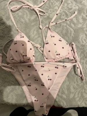 Ljusrosa bikini med körsbärsmönster🩷 XS - Jätte söt bikini med små röda körsbärs på, köpt i Lager157, nederdelen är aldrig använd! Säljer den för topdelen inte passade mig🩷 Storlek XS på både top och nederdelen🩷
