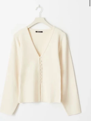  kofta med knappar från Gina Tricot - Stilren krämvit kofta från Gina Tricot med djup V-ringning och dekorativa knappar framtill. Koftan har lång ärm och rak passform, perfekt att matcha med både jeans och kjol. Mjukt material som känns skönt mot huden.