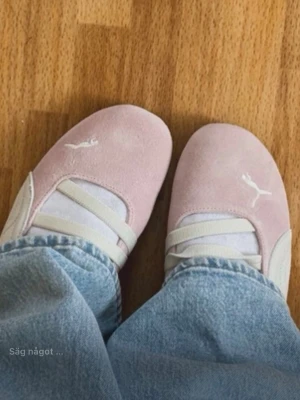 Ljusa rosa ballerinaskor från Puma - Säljer ett par ljusrosa ballerinaskor från Puma med vita detaljer och klassisk logga på ovansidan. Skorna har två elastiska band över foten för extra stil och passform. Perfekta för dig som gillar sportig och söt look. Storlek 38,5. Använda endast 1 gång