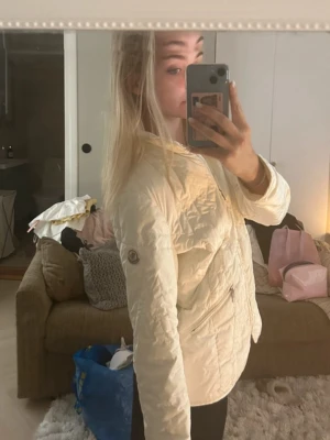 Vit pufferjacka från Moncler - Säljer en snygg vit pufferjacka från Moncler med dragkedja framtill och två fickor med dragkedja. Jackan har en klassisk Moncler-logga på ärmen och en lätt vadderad design. Varan är äkthetskontrollerad från sellpy där jag köpte den, bra skick.