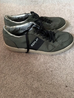 Replay gröna sneakers med svarta detaljer - Snygga gröna sneakers från Replay med svarta snören och svart detalj med logga på sidan. Ovandelen är i textil och sulan är vit med Replay-mönster undertill. Perfekta för en avslappnad och trendig stil.
