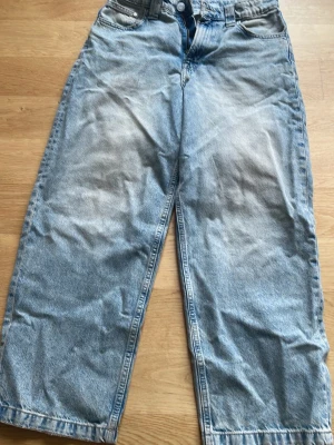 Baggy ljusblå jeans med raka ben - Säljer ett par baggy ljusblå jeans med raka ben och klassisk femficksdesign. Jeansen har en avslappnad passform och är tillverkade i denim. 