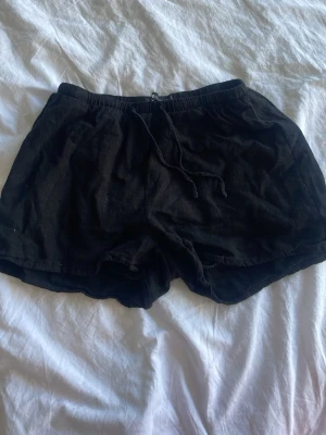 Svarta shorts från FB Sister - Svarta shorts från FB Sister i storlek S. De har en loose passform och är tillverkade i ett mjukt bomullsmaterial. Shortsens midja är elastisk med snörning för enkel justering. Perfekta för sommarens chill dagar.