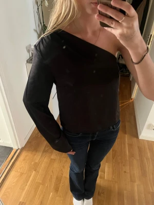 Svart oneshoulder topp - Säljer en svart oneshoulder topp med lång ärm på ena sidan. Superfin både till jeans, kostymbyxor eller kjol.