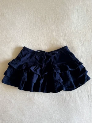 Mörkblå volangkjol - Supersöt mörkblå minikjol från Gina Tricot med volanger och snörning i midjan. Aldrig använd