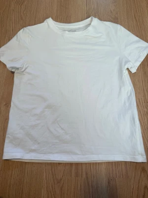 Vit basic t-shirt från H&M - En klassisk vit t-shirt från H&M i mjuk bomull. T-shirten har rund halsringning och korta ärmar. Den har aldrig använts men har ingen prislapp.
