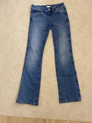 Blå bootcut jeans med broderade fickor - Jättesnygga blå bootcut jeans med klassisk tvätt och broderade detaljer på bakfickorna. Hade även passat till att göra om till ett par snygga shorts! 