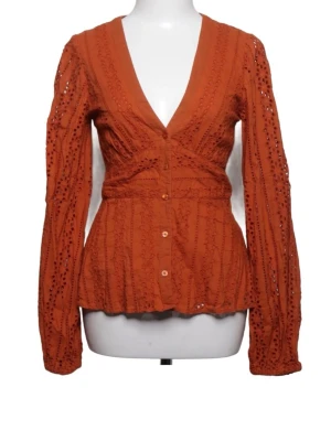  Blus med knappar - Rustfärgad blus med djup v-ringning och dekorativa spetsdetaljer. Blusen har långärmade ärmar med broderade hålmönster och knappar framtill. Materialet är lätt och luftigt, perfekt för att skapa en cool och trendig look. Köpt på sellpy men endast testad då den inte passade mig :)