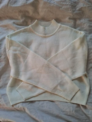 Vit stickad tröja H&M S - Enkel, vit stickad tröja från H&M Divided. Tröjan har en ribbad hög krage och långa ärmar med ribbade muddar. Storlek S, lite lätt oversized💕