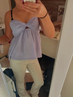 Ljuslila omlott linnetopp - Säljer en ljuslila omlott linnetopp med twistad detalj framtill och liten cut-out under bysten. Toppen är ärmlös och har en luftig, flowy passform som passar perfekt till sommaren.
