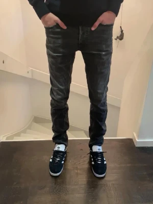 Diesel Jeans - Säljer ett par svarta slim fit jeans med coola slitningar och tvättad look. Jeansen har klassisk femficksdesign och är tillverkade i stretchigt material som sitter snyggt och bekvämt. Perfekta för dig som gillar en modern och avslappnad stil.