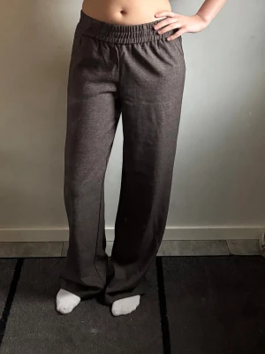 Bruna mjukisbyxor med raka ben - Säljer ett par bruna byxor med raka ben och resår i midjan. Byxorna är tillverkade i ett mjukt och bekvämt material som passar perfekt för chill dagar. De har en enkel design utan fickor eller logga, och är riktigt sköna att ha på sig.