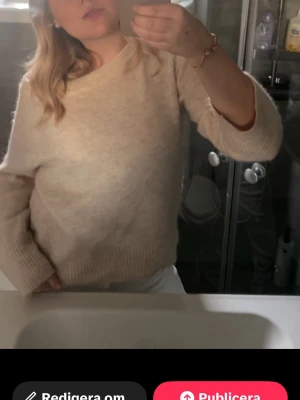 Beige stickad tröja med rund hals - Mysig beige stickad tröja med rund hals och långa ärmar. Tröjan har ribbade muddar vid ärmslut och nederkant, perfekt för att hålla värmen. Enkel och stilren design som passar till många olika outfits.