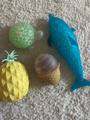 Fyra squishies i olika former - Säljer ett set med fyra squishies i mjukt gummi: en blå delfin, en gul ananas, en grön sköldpadda och en glass i bägare. Perfekta som stressleksaker eller dekoration. Färgglada och roliga former som passar både skrivbordet och väskan.