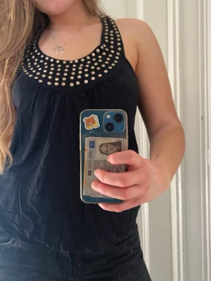 Svart linnetopp med nitar - Snygg svart linnetopp med bred ringning dekorerad med silvriga nitar. Kan användas som klänning 