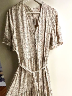 Newbie klänning - Köptes förra sommaren. Aldrig använd med prislappen kvar. Superfin lång modell med korta ärmar och knappar. Skärp runt midjan. Pris går att diskutera vid snabb affär!