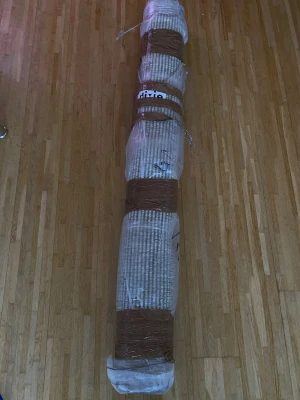 Inplastad rullad matta - Säljer en rullad matta som är inplastad och tejpad med brunt tejp. Mattan har ett mönster i beige och vitt och är av textilmaterial. Perfekt för dig som vill ha en stilren och enkel matta till hemmet.