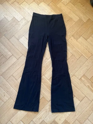 Svarta utsvängda leggings - Säljer ett par svarta leggings med utsvängda ben. De har hög midja och är gjorda i ett stretchigt material som sitter skönt på kroppen. Perfekta för dig som gillar en enkel men trendig look. 