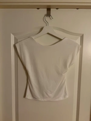 Vit topp med öppen rygg -  Vit topp med öppen rygg. Toppen har en croppad och tajt passform. Storlek M från Stradivarius! Helt ny med prislapp🫶🏼