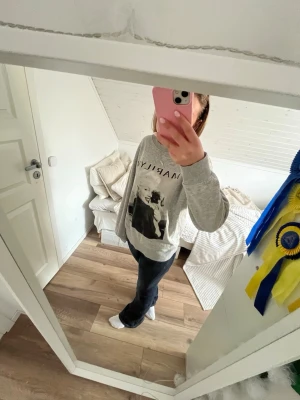 Grå sweatshirt med tryck  - Cool grå sweatshirt med stort svartvitt Marilyn Monroe-tryck framtill och texten 'MARILYN' ovanför. Tröjan har rund halsringning och långa ärmar. Perfekt för en avslappnad och trendig stil.
