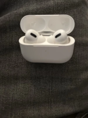 Apple AirPods Pro vita in-ear - Säljer ett par vita Apple AirPods Pro med laddningsfodral. De har en stilren och kompakt design med silikonpluppar för bra passform. Perfekta för trådlös musik och samtal, och kommer med brusreducering. Materialet är plast och fodralet är magnetiskt.