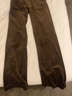 Bruna mjukisbyxor i velour - Ett par fina mysiga juciy byxor i färgen brun. Dem är uppsydda och passa folk 159-163 beroende på hur man har dem alltså vikta där uppe vid midjan men annars typ nya fast två färg prickar upp vid fickan men det syns inte särskilt mycket.
