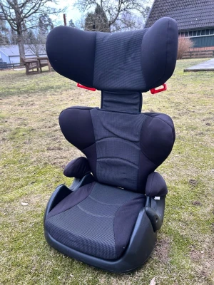 Svart bältesstol för barn - Säljer en svart bältesstol för barn med justerbart nackstöd och vadderade sidor. Stolen har detaljer i rött och är tillverkad i slitstark plast och tyg. Passar perfekt i bilen för att ge extra säkerhet och komfort under resan.