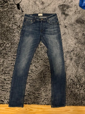 Jack and Jones jeans  - Snygga jack and Jones blå jeans i slim fit-modell med lätt slitna detaljer och klassisk femficksdesign. Nypris-800kr mitt pris-300kr, storlek W29/L34 men passar som L32 nyskick använd max 4 gånger 