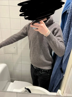 Mörkgrå hoodie i merinoull  - Säljer en stilren mörkgrå hoodie med huva och långa ärmar. Tröjan är gjord i mjuk merinoull och har ribbade muddar vid ärmslut och nederkant. Perfekt för dig som gillar en enkel men snygg look.