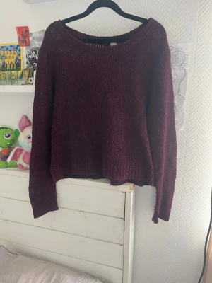 Vinröd stickad tröja från Divided - Mysig vinröd stickad tröja från Divided med avslappnad passform och rund halsringning. Tröjan har långa ärmar och är tillverkad i ett mjukt, lätt material som passar perfekt till höst och vinter.