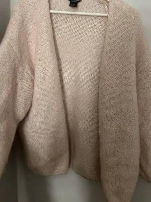 Ljusrosa stickad kofta från Lindex - Mysig ljusrosa stickad kofta från Lindex med avslappnad passform och öppen front. Storlek M/L men passar för S också!