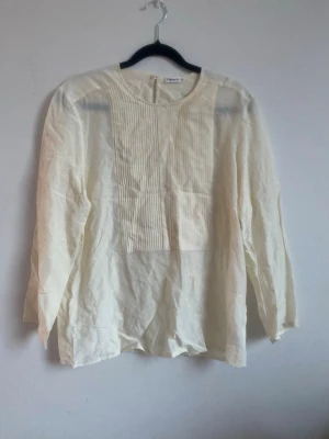 Stilren snygg cremfärgad blus/skjorta - Jättesnygg vit blus/skjorta från Filippa K med snygga detaljer framtill. Storlek XS men är ganska stor i storlek. Lite genomskinlig (syns på bilderna). Accepterar rimliga prisförslag!