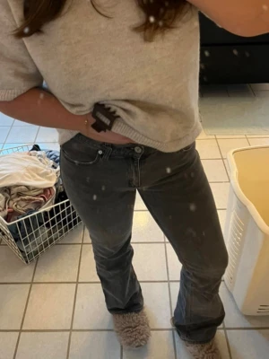Grå bootcut jeans med mid waist - Snygga grå jeans med bootcut-modell och mid waist. Jeansen har klassiska fyra fickor och stängs med knapp och dragkedja. Perfekta för en avslappnad men trendig look. Materialet ser ut att vara denim i bomullsblandning.
